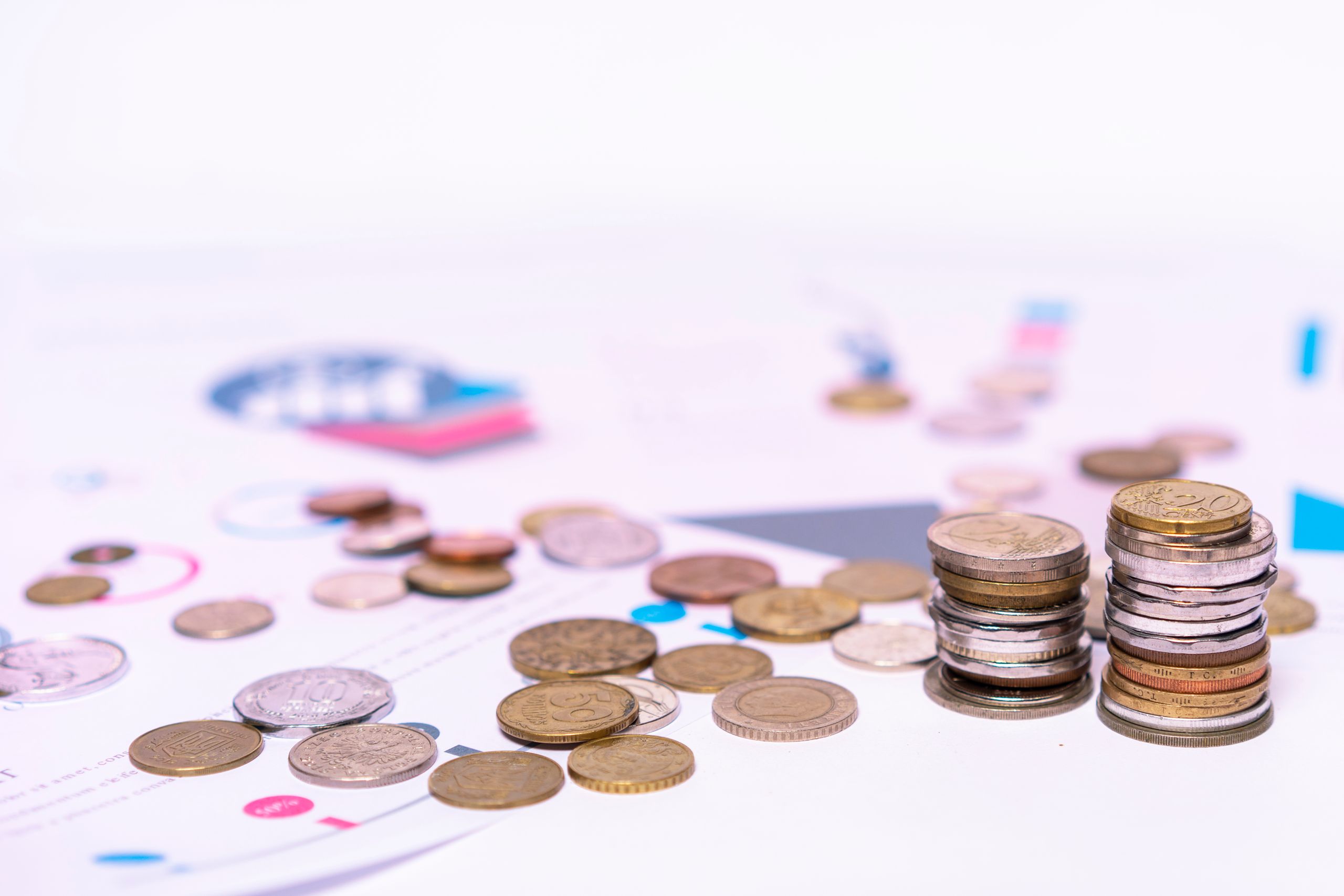 PGD and IVF 5 Stack of assorted coins with financial documents on a white background, highlighting the concept of savings.